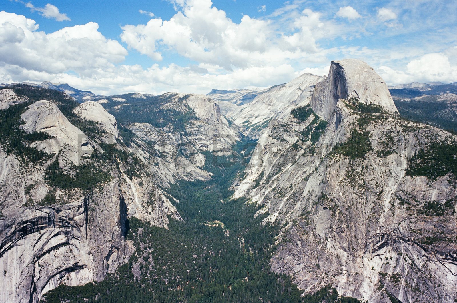 Elevated view down Yosemite Valley towards Half Dome granite peak under dramatic clouds. Elevated view down Yosemite Valley towards Half Dome granite peak under dramatic clouds.